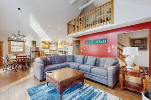 A spacious living area with a sectional sofa, a wooden coffee table, and a red accent wall.