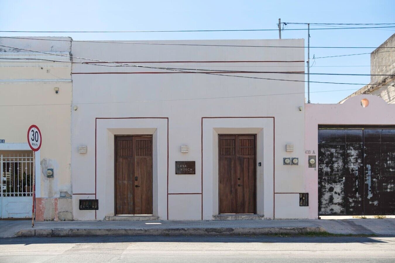 A building with two wooden doors, a speed limit sign, and a garage door.