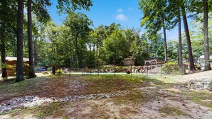 A fenced outdoor area with trees, a small structure, and a paved path. - 3-story condo near skiing with Ping-Pong, foosball, fireplace, balcony, & W/D (North Conway)