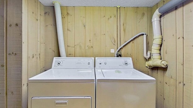 A laundry room with two stacked washers and dryers, wooden walls, and visible plumbing. - 3-story condo near skiing with Ping-Pong, foosball, fireplace, balcony, & W/D (North Conway)