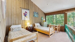 A cabin-style room with two wooden beds, a desk, and a window overlooking a forest. - 3-story condo near skiing with Ping-Pong, foosball, fireplace, balcony, & W/D (North Conway)