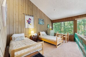 Ein blockhaushaltiges Zimmer mit zwei Holzbetten, einem Schreibtisch und einem Fenster mit Blick auf einen Wald.