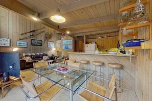 Une cuisine moderne avec des meubles en bois, un coin bar et une table à manger avec des tabourets de bar.