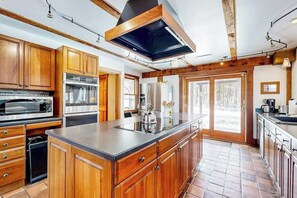 A spacious kitchen with wooden cabinets, stainless steel appliances, and a large island. - Stunning home with Moore Reservoir views and private sunroom (Littleton)
