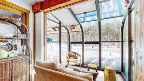 A cozy room with a large window, a wicker shelf, a sofa, and a small round table.