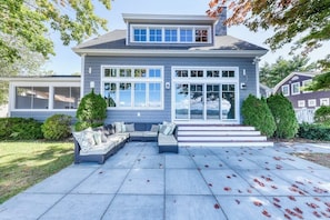 A two-story house with a covered patio, large windows, and a well-maintained lawn.
