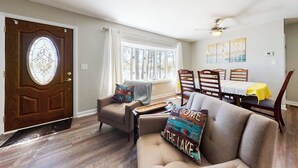Una sala de estar con sofá, sillón, mesa de comedor y sillas.