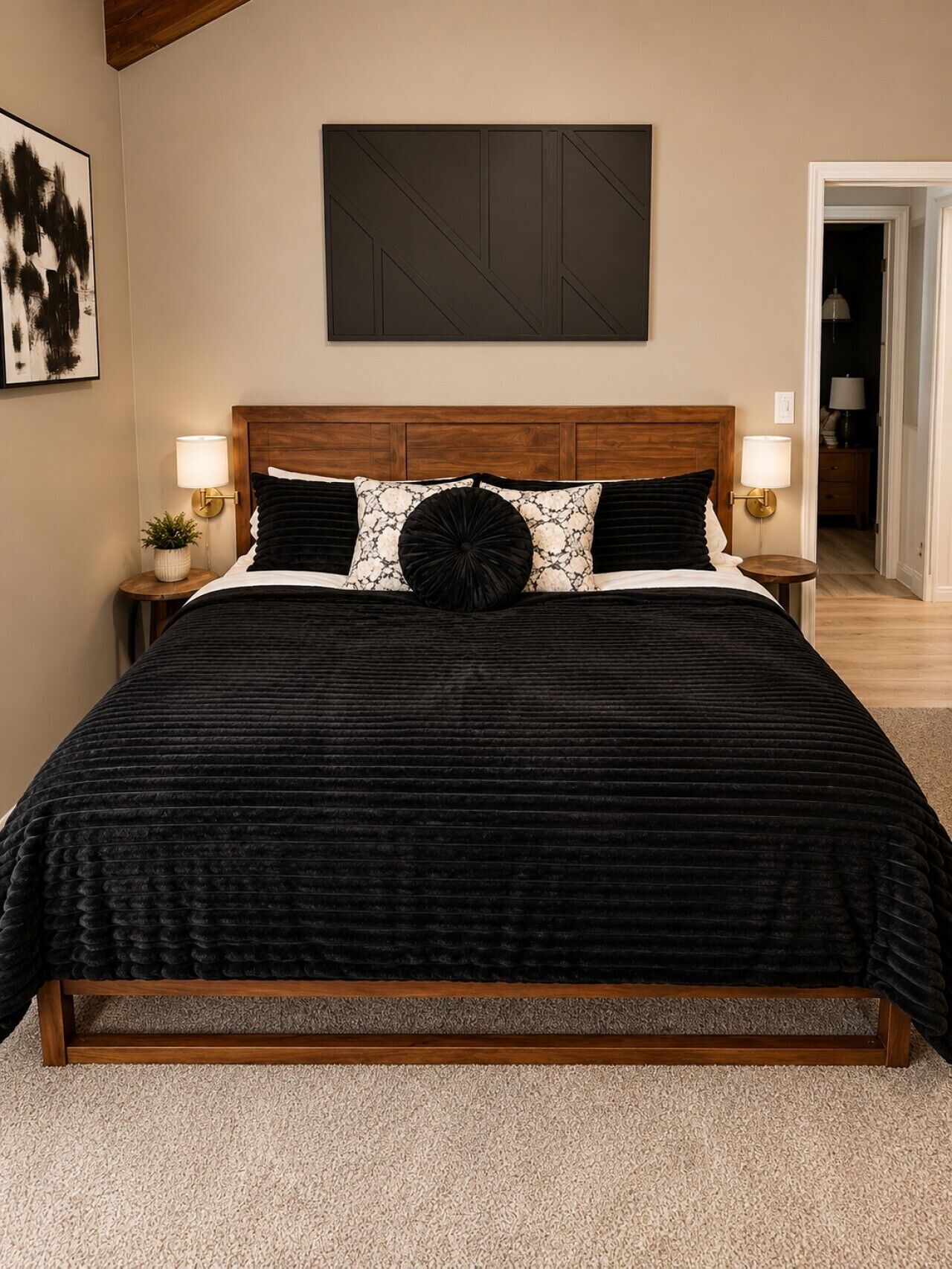 A bedroom with a large bed, two bedside tables with lamps, a wooden headboard, and a framed picture on the wall.