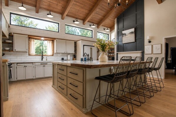 A modern kitchen with a large island, bar stools, and a view of the outdoors.