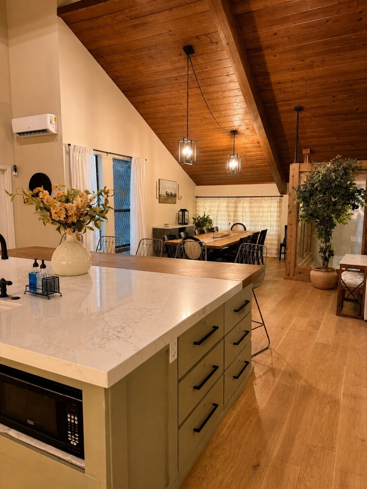 A kitchen with a marble countertop, wooden cabinets, a built-in microwave, and a dining area with a table and chairs.