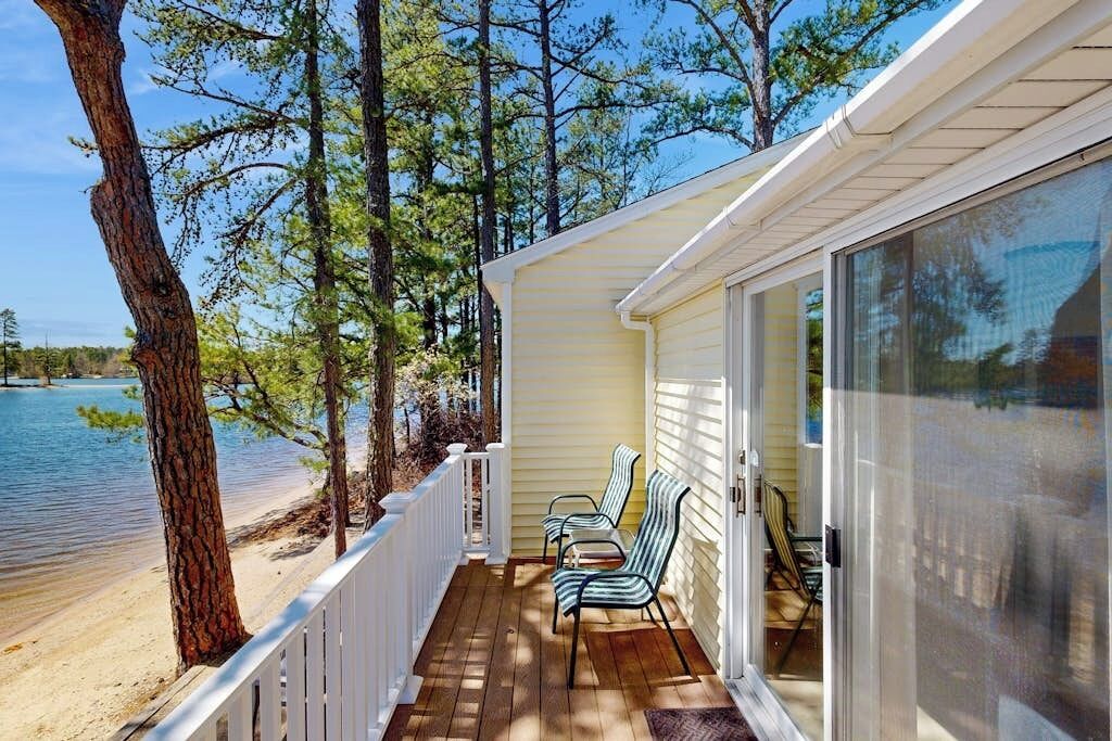 Une véranda avec deux chaises, une vue sur un lac et une balustrade blanche.