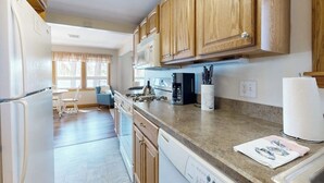 A kitchen with wooden cabinets, a microwave, a coffee maker, and a dishwasher. - Lakefront home with private beach, access to dock/fishing/kayaks/boat slip (Ossipee)