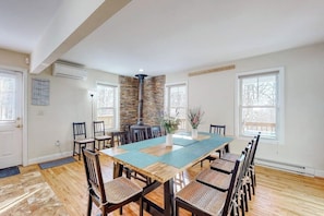 Comedor con una larga mesa de madera, sillas, pared decorativa de piedra y chimenea.