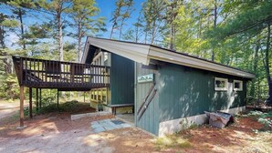 Eine kleine Holzhütte mit einer Holzterrasse, einer überdachten Veranda und einem Feldweg, der zum Eingang führt.