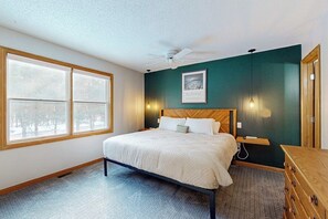 Ein Schlafzimmer mit einem Bett, einem Deckenventilator, einem Fenster, einem Wandbild und einer Kommode.