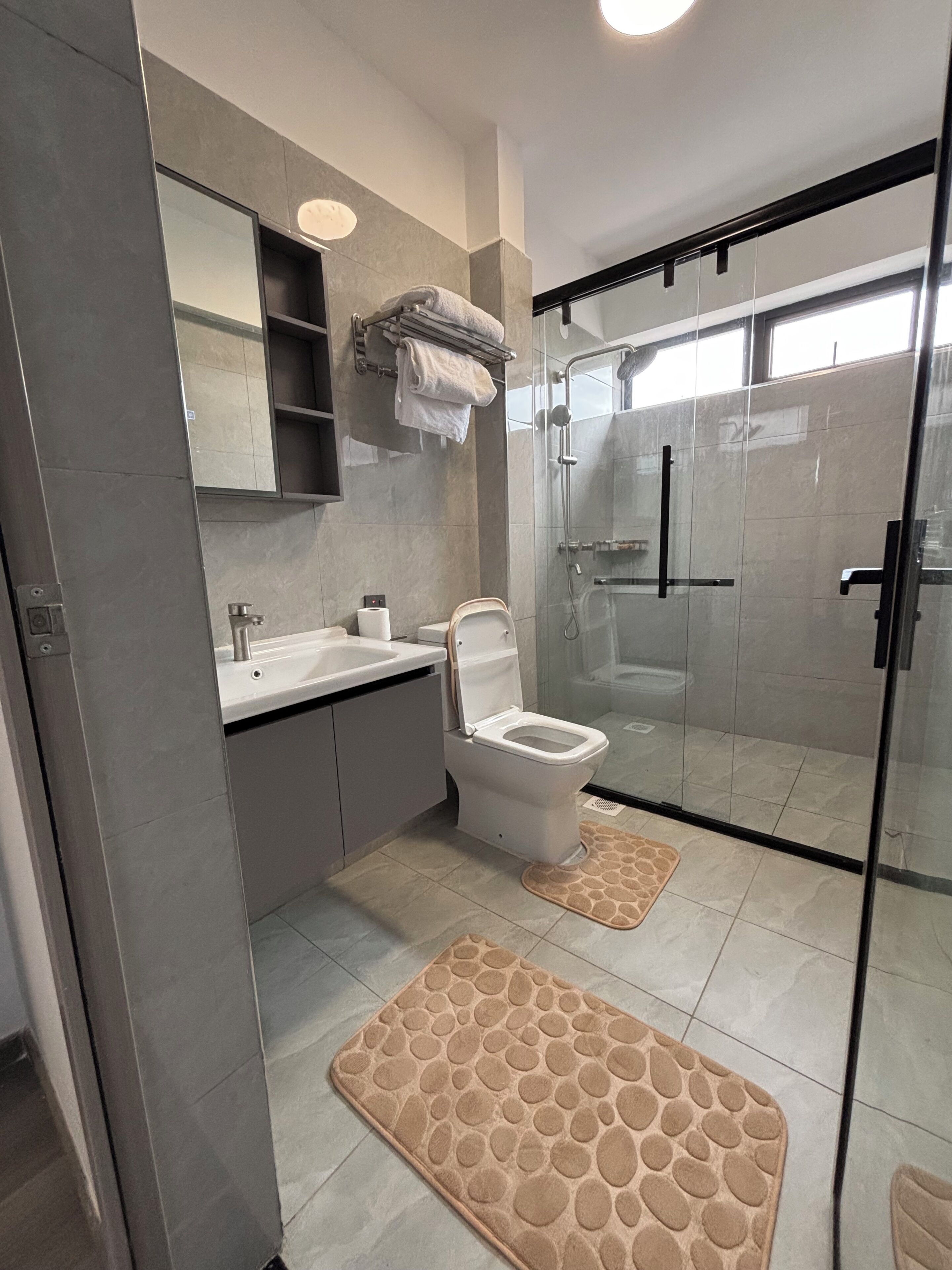 Un baño moderno con ducha de vidrio, inodoro y lavamanos.