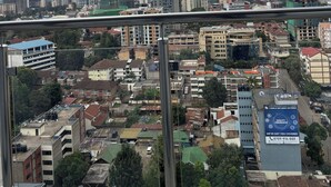 A cityscape with a mix of residential and commercial buildings, a clear sky, and a billboard advertising insurance. - 2-bedroom apartment on 18th floor in adorable Nairobi with fitness room access, (Nairobi)