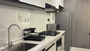 A modern kitchen with a stainless steel sink, a gas stove, a built-in oven, and a refrigerator. - 2-bedroom apartment on 18th floor in adorable Nairobi with fitness room access, (Nairobi)