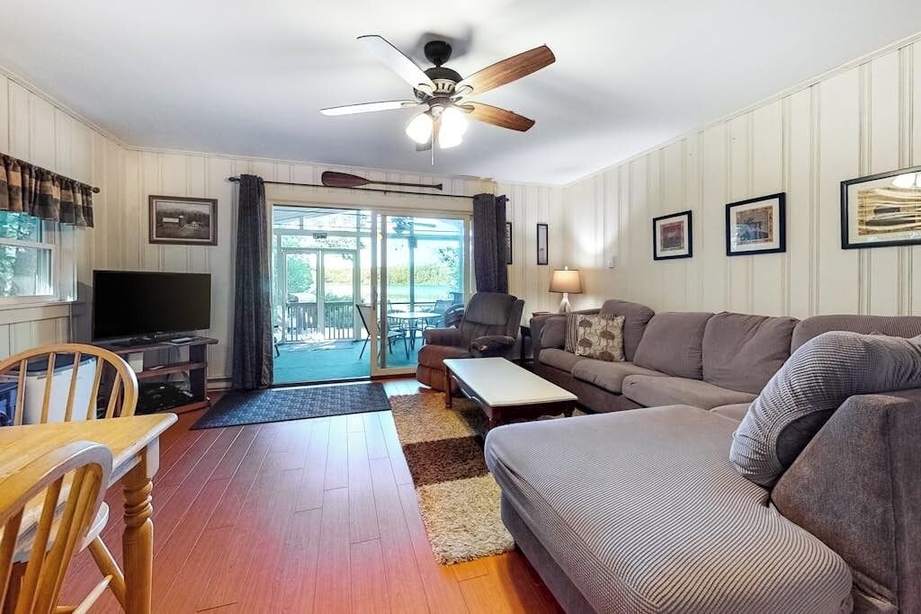 A living room with a ceiling fan, a television, a sofa, a coffee table, and a dining area with a table and chairs.