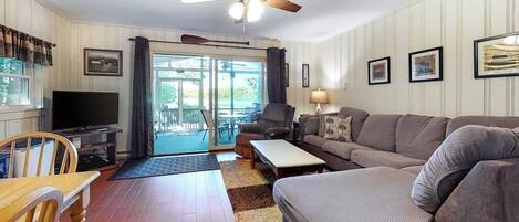A living room with a ceiling fan, a television, a sofa, a coffee table, and a dining area with a table and chairs.