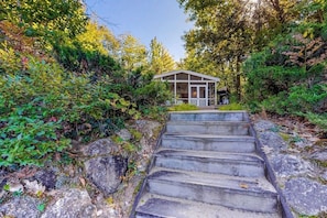 A house with a porch, surrounded by trees and a stone staircase. - Lakefront cottage on Big Pea Porridge Pond w/ private dock, beach, kayaks, canoe (Madison)