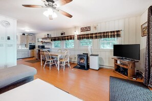 A cozy living room with a fireplace, a television, and a dining area. - Lakefront cottage on Big Pea Porridge Pond w/ private dock, beach, kayaks, canoe (Madison)