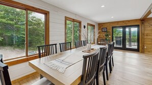A dining area with a large table, chairs, and large windows with a view of trees. - Spectacularly updated family mountain lodge w/deck & amazing views (Madison)