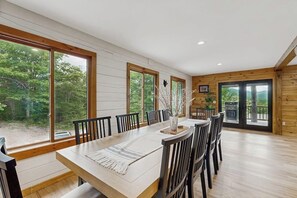 A dining area with a large table, chairs, and large windows with a view of trees. - Spectacularly updated family mountain lodge w/deck & amazing views (Madison)