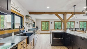 A modern kitchen with wooden beams, large windows, and a central island. - Spectacularly updated family mountain lodge w/deck & amazing views (Madison)