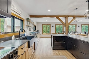 A modern kitchen with wooden beams, large windows, and a central island. - Spectacularly updated family mountain lodge w/deck & amazing views (Madison)