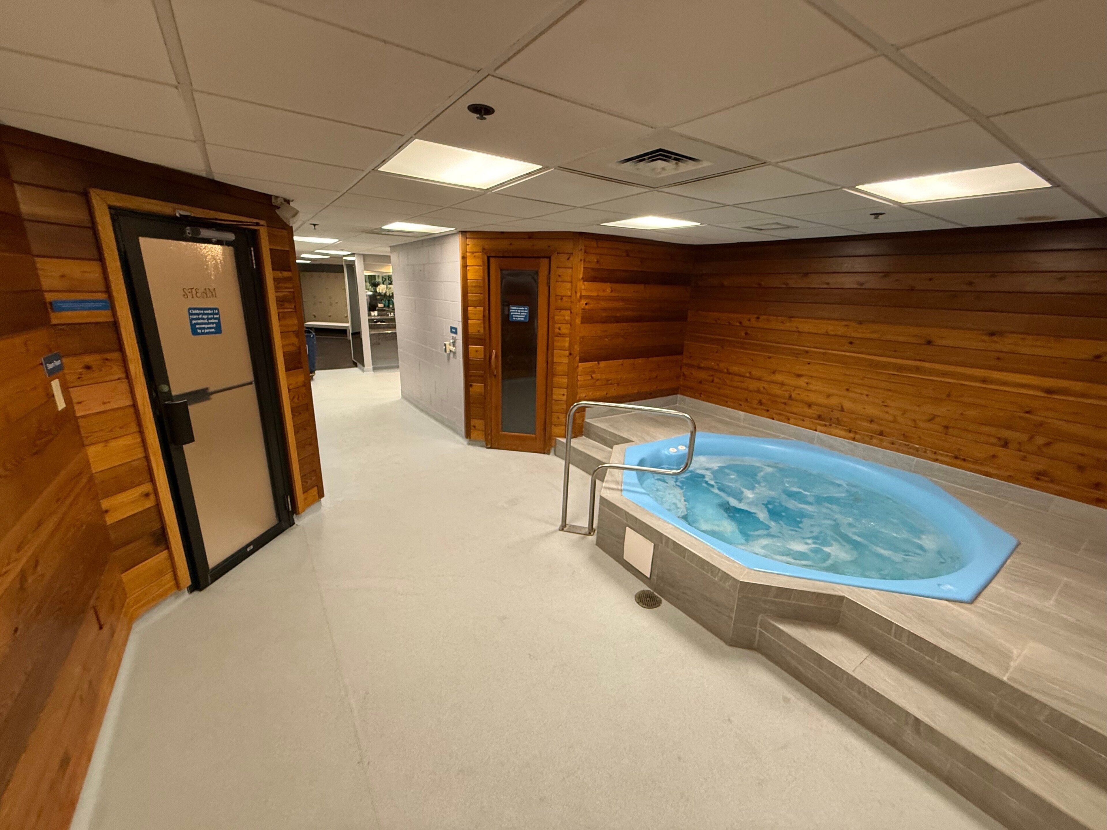 Un área de spa con una bañera de hidromasaje, paredes de madera y suelo de baldosas.