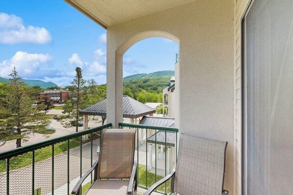 Ein Balkon mit Blick auf einen Park, ein Gebäude und Hügel.