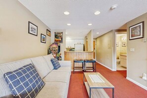 Ein Wohnzimmer mit einer Couch, einem Couchtisch und einer Küche im Hintergrund.