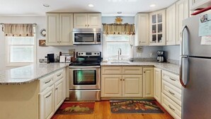 Una cocina con armarios blancos, electrodomésticos de acero inoxidable y encimera de granito.