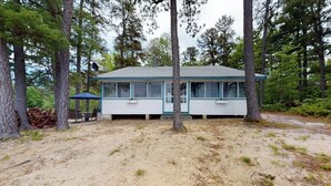 Une cabane à un seul étage, dotée d’un toit à pignon et entourée d’arbres.