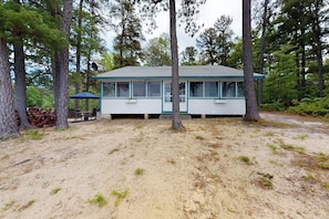 Una cabana d'un pis amb teulada a dos vessants, envoltada d'arbres.