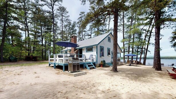 Une cabane avec une terrasse, un barbecue et vue sur le lac.