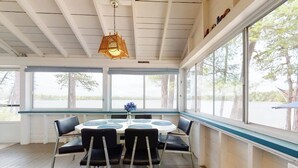 Un espace repas abrité, avec une table ronde, des chaises et un luminaire suspendu.