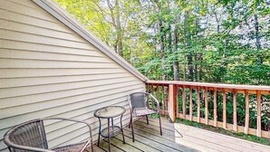 A wooden deck with two wicker chairs and a small round table.