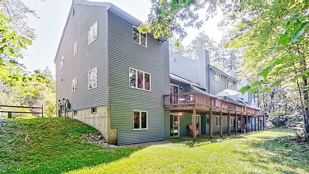 A two-story house with a balcony, a covered porch, and a grassy yard.