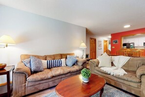 Ein Wohnzimmer mit zwei Sofas, einem Couchtisch und einer Küche im Hintergrund.