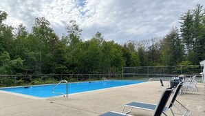 En swimmingpool med solstolar och ett staket.