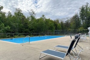 Ein Pool mit Liegestühlen und einem Zaun.