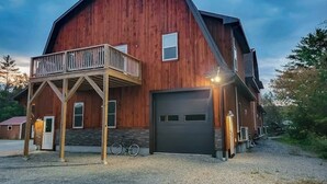 A large wooden barn-style building with a garage, a balcony, and a bicycle parked outside.