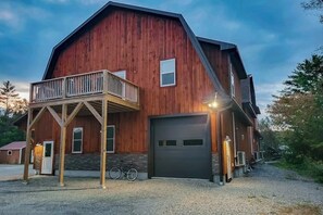 A large wooden barn-style building with a garage, a balcony, and a bicycle parked outside. - Mountain view retreat with furnished deck, kitchen, gas grill, & washer/dryer (Littleton)