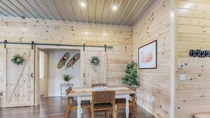 A wooden interior with a dining table, chairs, a bench, a wall-mounted coat rack, and a framed picture.