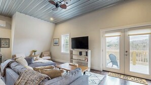 A living room with a sofa, television, and a sliding glass door leading to a deck.