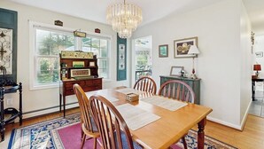 Comedor con una mesa de madera, sillas, una araña y una alfombra.