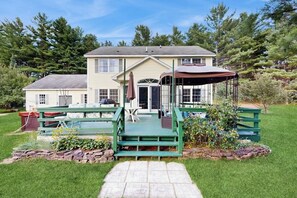 A two-story house with a covered porch and a stone pathway leading to the entrance. - Private spacious mountain view w/ beach rights, hot tub, spacious deck & firepit (Ossipee)