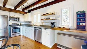Una cocina moderna con armarios blancos, electrodomésticos de acero inoxidable y vigas de madera.